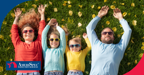 Family of four lying on grass in the park wearing colorful sweaters and sunglasses