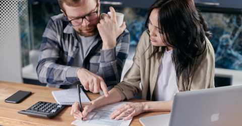 A couple reviewing financial documents with a calculator and laptop