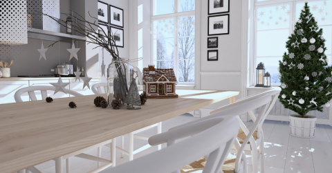 Festive dining room with Christmas tree, gingerbread house, and winter-themed decor.