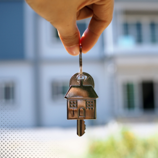 a hand holding a house shaped key chain and a key